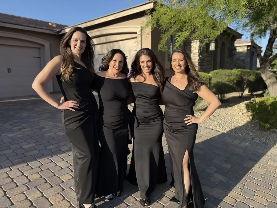 Four friends in black gowns before a gala